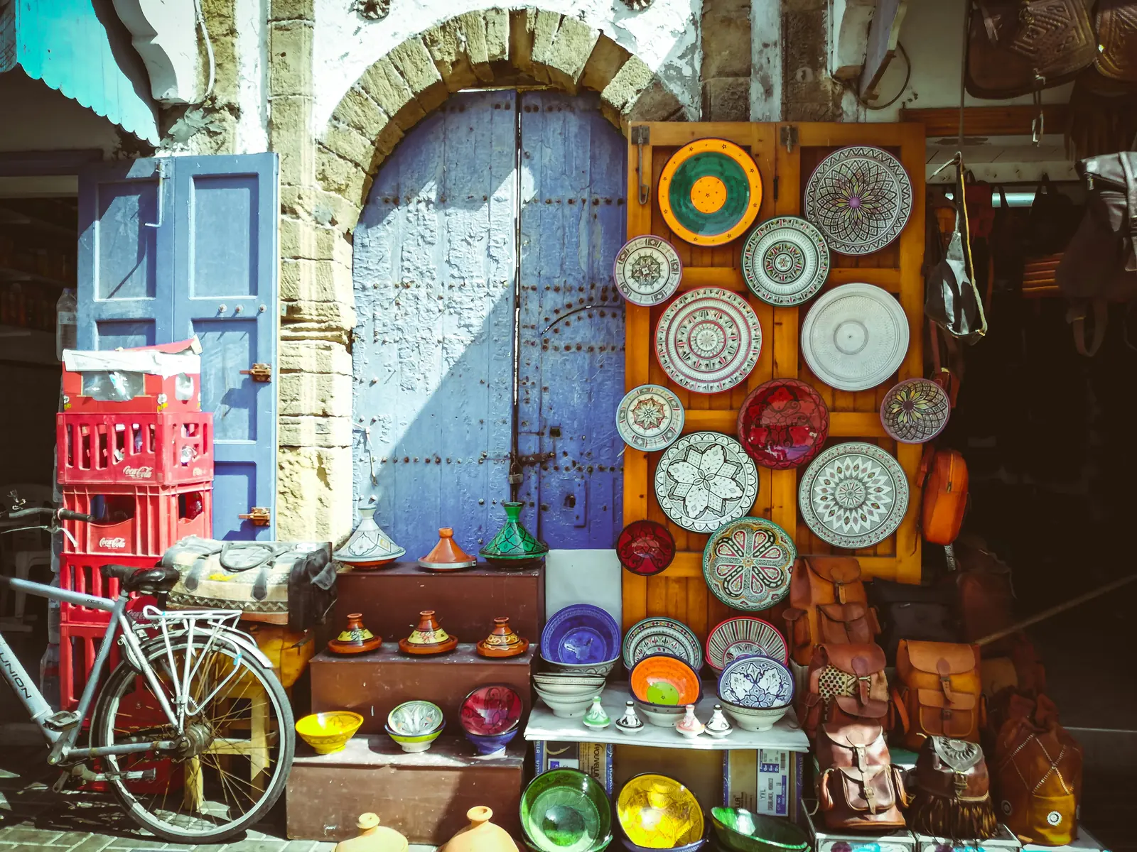 Devanture d'échoppe dans les souks d'Essaouira : porte bleue, poteries peintes et maroquinerie