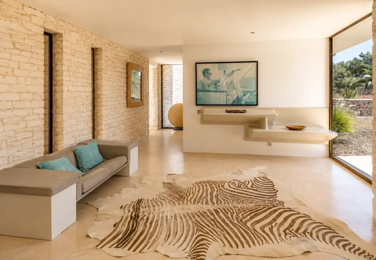 Hall d'entrée de la Villa Nausikaa avec banquette, mur en pierre sèche et photographie grand format
