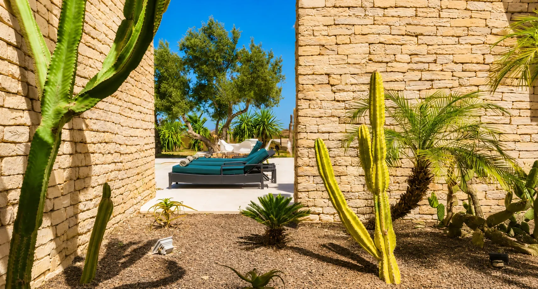 Passage entre deux murs en pierre sèche et jardin de cactus de la Villa Nausikaa