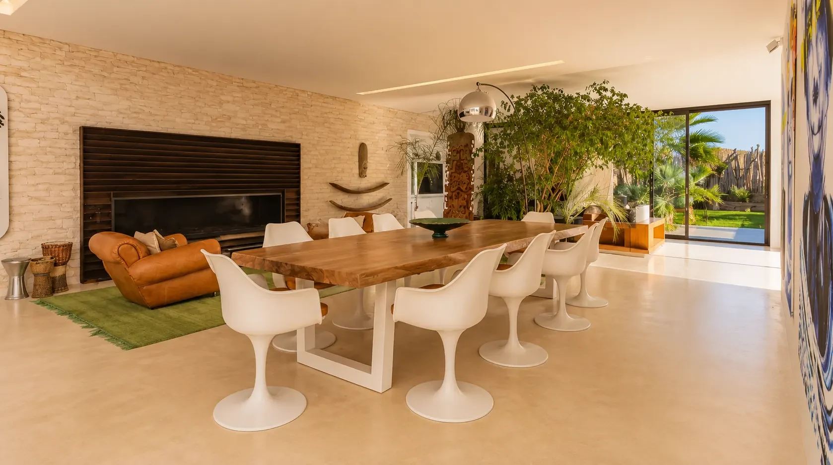 Salle à manger de la Villa Nausikaa, cheminée murale en pierre et baies ouvertes sur le jardin