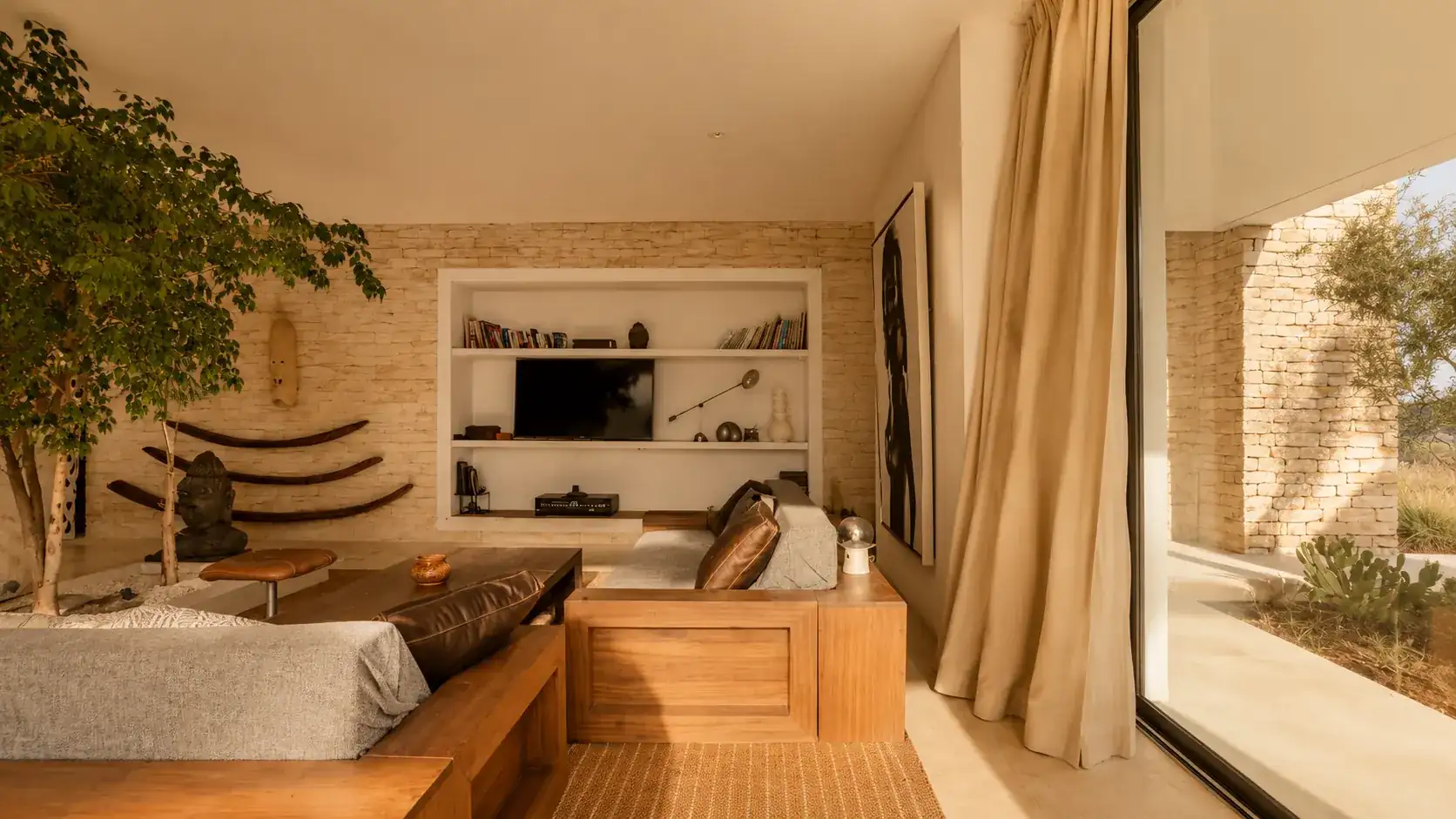 Coin salon en pierre claire avec téléviseur intégré et Bouddha en pierre à la Villa Nausikaa