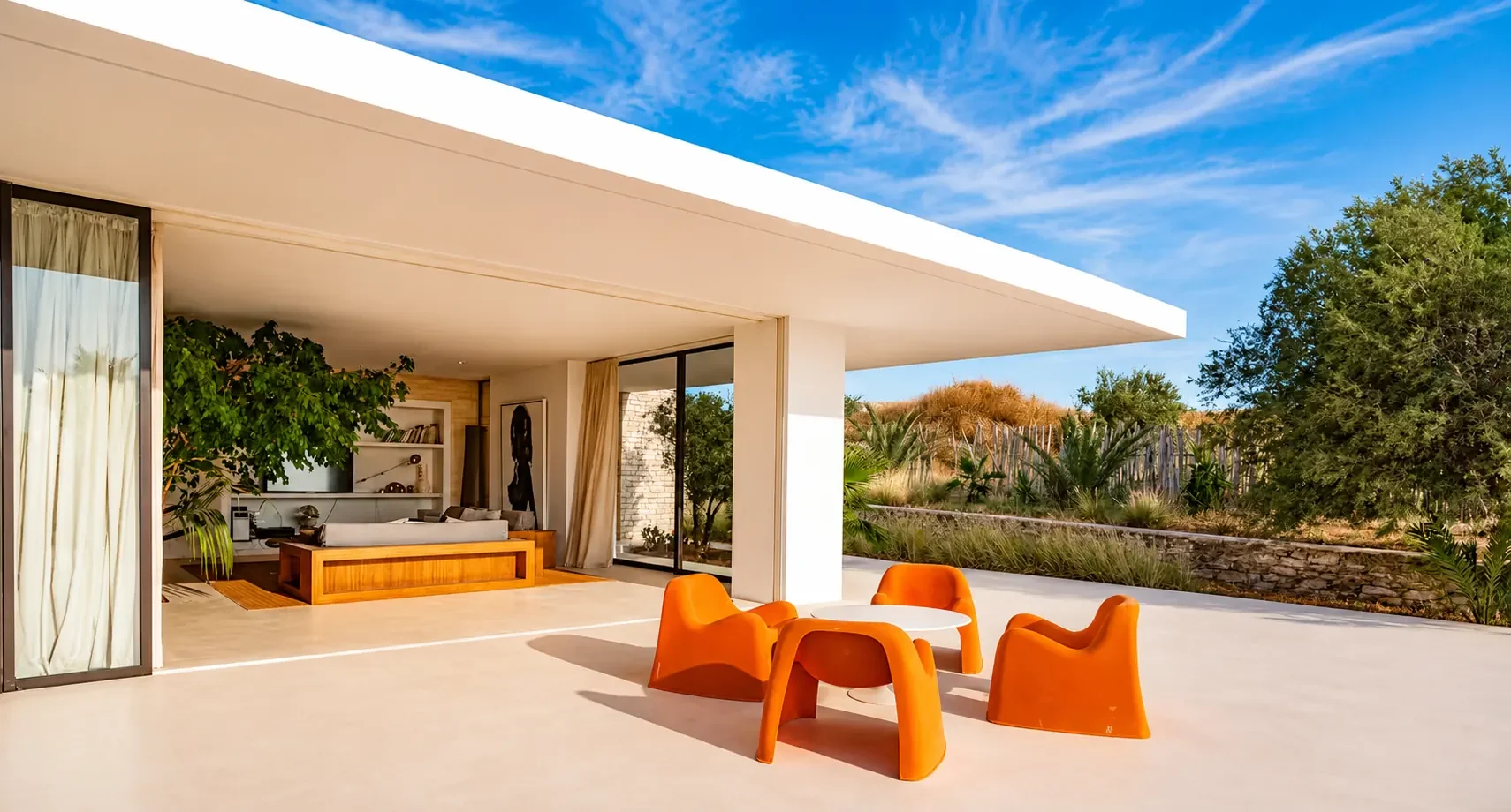 Terrasse couverte de la Villa Nausikaa prolongeant le séjour, fauteuils orange et jardin sec