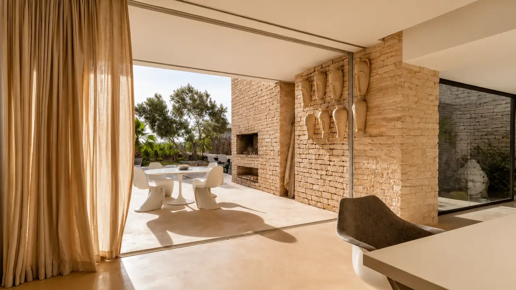 Baies coulissantes ouvertes sur la terrasse à manger et son foyer extérieur, Villa Nausikaa