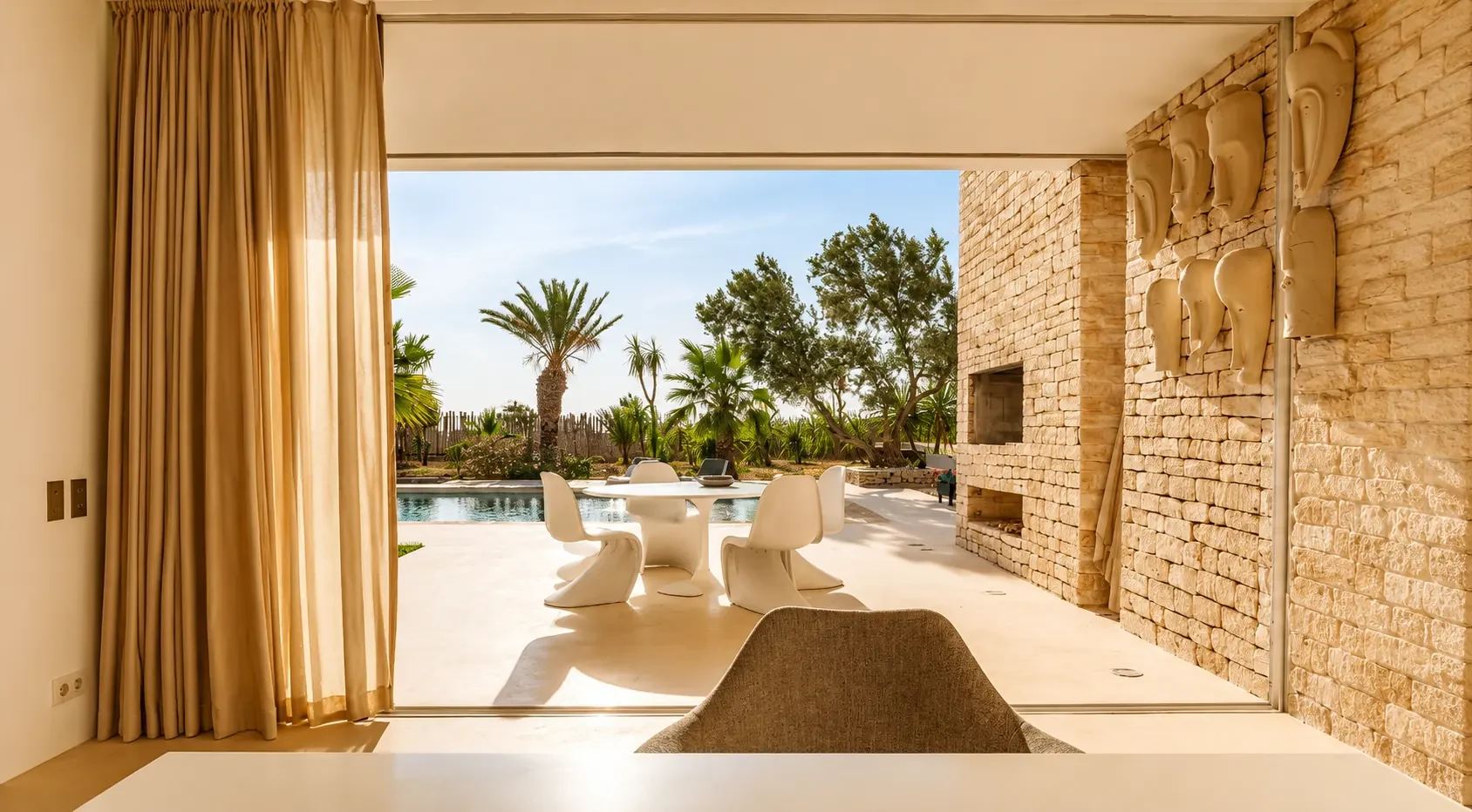Terrasse à manger ouverte sur la piscine et la palmeraie de la Villa Nausikaa, à Essaouira